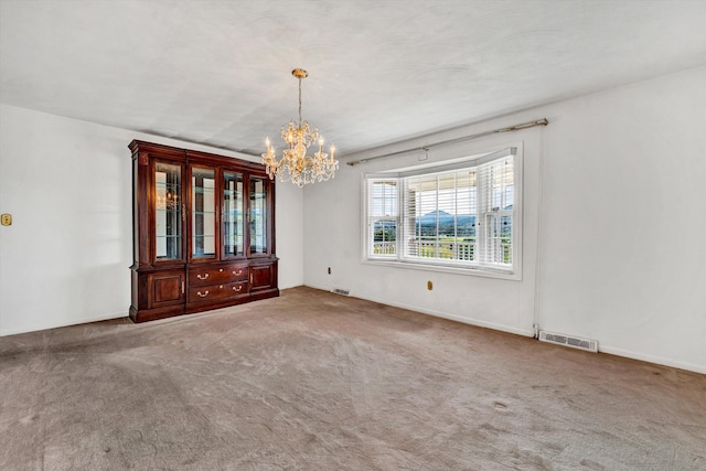 carpeted spare room with visible vents and a chandelier