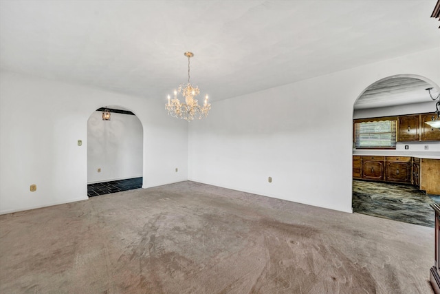 unfurnished dining area with arched walkways, dark colored carpet, and a chandelier