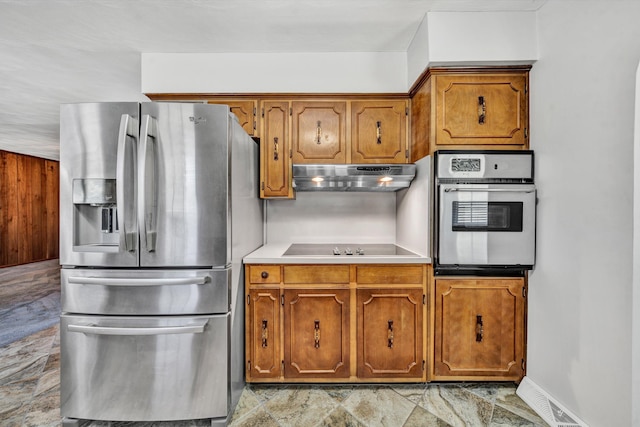 kitchen featuring baseboards, brown cabinetry, stainless steel appliances, light countertops, and under cabinet range hood