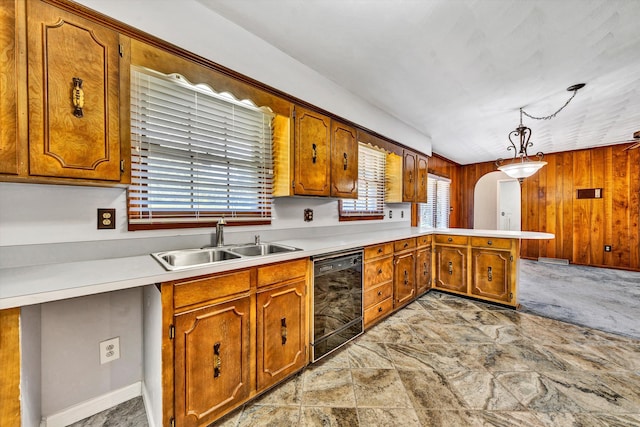 kitchen featuring wooden walls, dishwasher, a peninsula, light countertops, and a sink