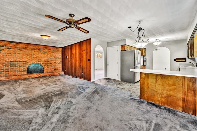 kitchen featuring carpet floors, appliances with stainless steel finishes, arched walkways, and a sink