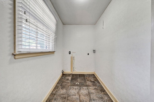 clothes washing area featuring stone finish floor, laundry area, and baseboards