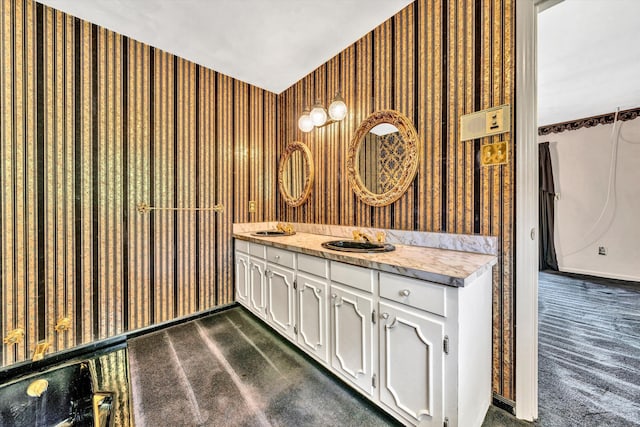 bathroom featuring double vanity, a sink, and wallpapered walls