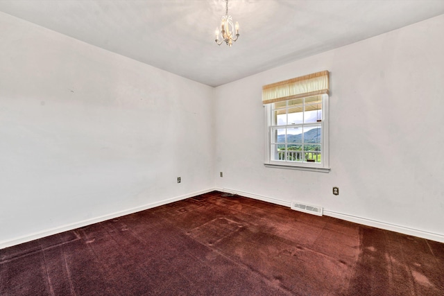 carpeted spare room featuring baseboards, visible vents, and a notable chandelier