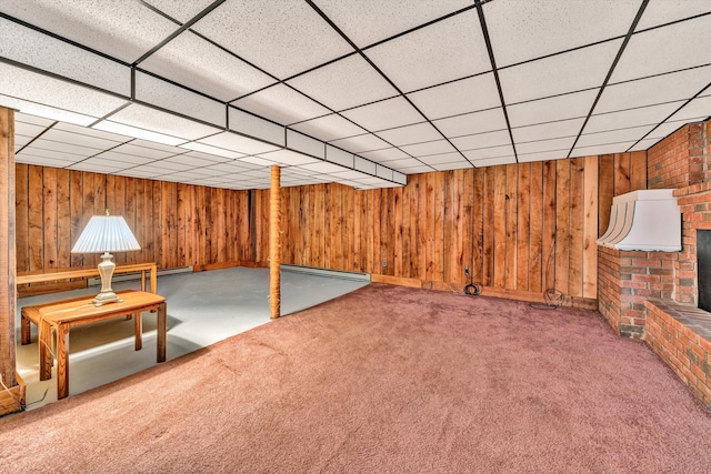 finished below grade area featuring a brick fireplace, carpet flooring, wood walls, and baseboard heating