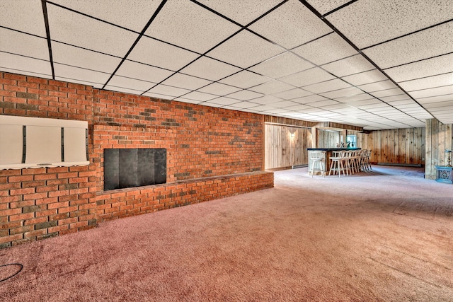 unfurnished living room with brick wall, a dry bar, carpet flooring, and a paneled ceiling