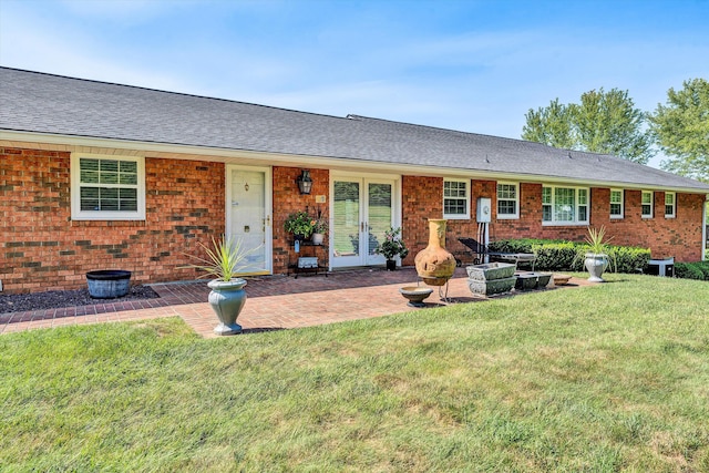 back of property with a shingled roof, french doors, a yard, a patio area, and brick siding