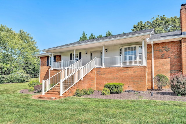 single story home featuring a front yard, covered porch, brick siding, and a chimney