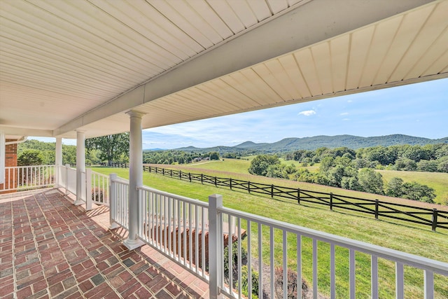 view of patio / terrace featuring covered porch, a rural view, fence, and a mountain view