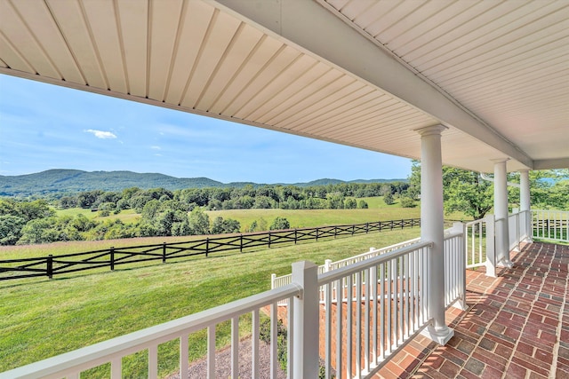 view of patio with covered porch, a rural view, fence, and a mountain view