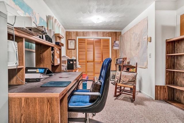 carpeted home office with ornamental molding, built in desk, and a textured ceiling