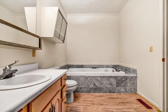 bathroom with vanity, hardwood / wood-style floors, tiled bath, and toilet