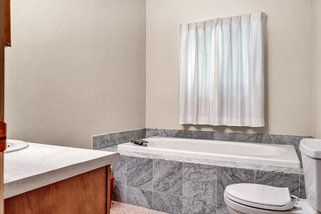 bathroom featuring vanity, tiled bath, and toilet