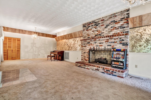 unfurnished living room featuring a brick fireplace, carpet flooring, and an inviting chandelier