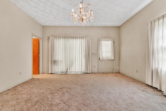 carpeted empty room featuring an inviting chandelier