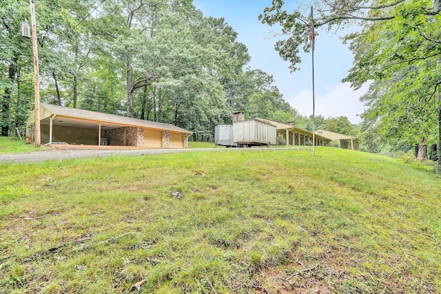 view of yard featuring a garage, an outbuilding, and a carport