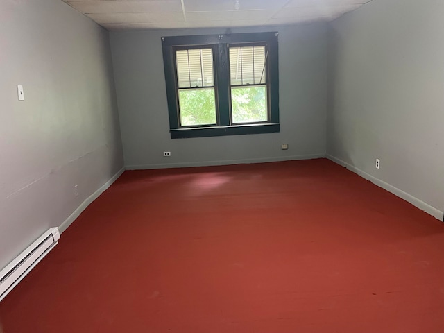 empty room featuring a drop ceiling and a baseboard heating unit