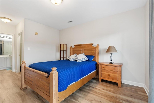 bedroom featuring ensuite bathroom and light wood-type flooring