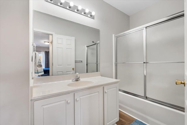 bathroom featuring hardwood / wood-style flooring, vanity, and shower / bath combination with glass door