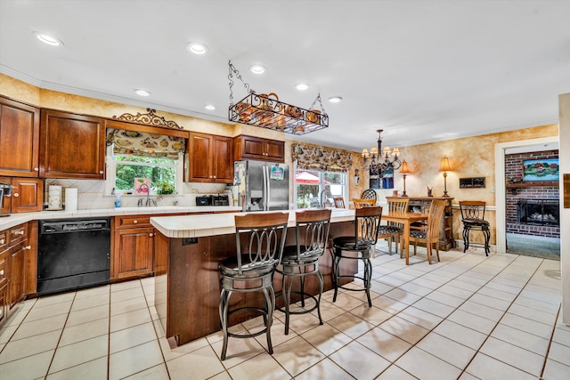 kitchen with black dishwasher, stainless steel fridge, a fireplace, light tile patterned floors, and a center island