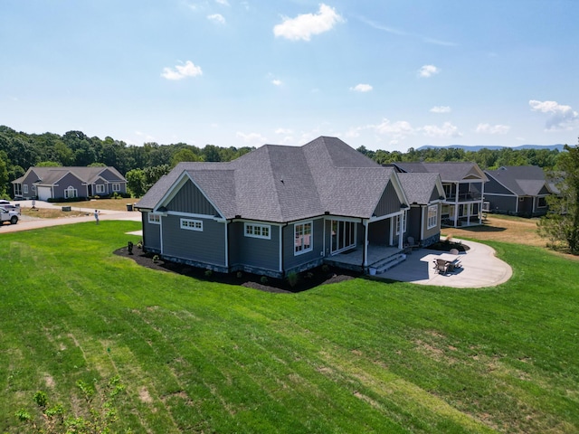 back of house featuring a lawn, board and batten siding, and a shingled roof