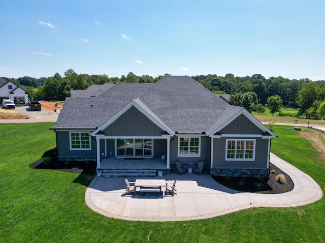 rear view of property with board and batten siding, a patio area, a lawn, and roof with shingles