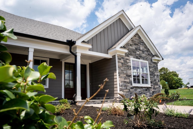 exterior space with covered porch, board and batten siding, and roof with shingles