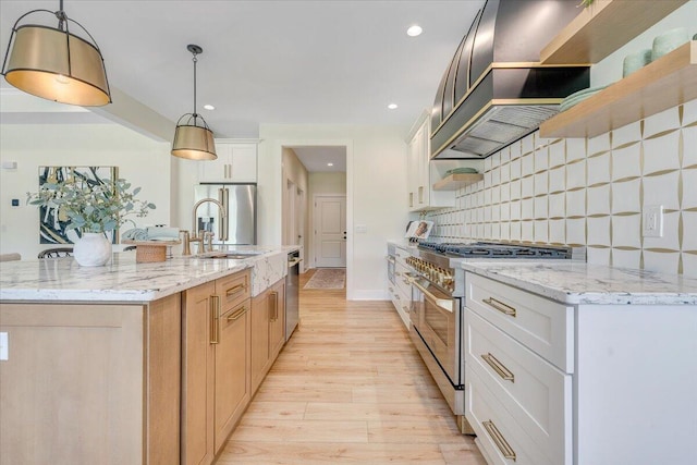 kitchen with a sink, backsplash, light wood-style floors, stainless steel appliances, and open shelves