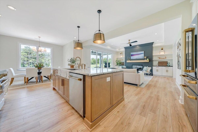 kitchen with light wood-style flooring, brown cabinetry, appliances with stainless steel finishes, and a large fireplace