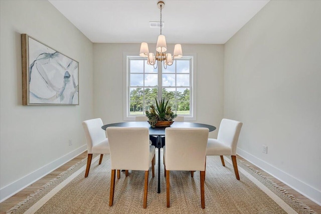 dining area featuring visible vents, baseboards, an inviting chandelier, and light wood-style flooring