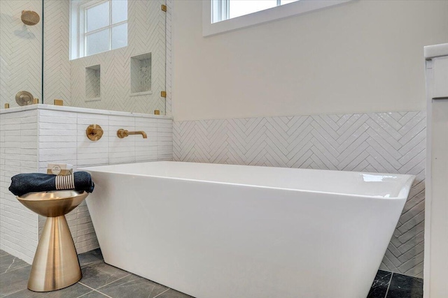 full bath with tile walls, tile patterned floors, and a freestanding bath