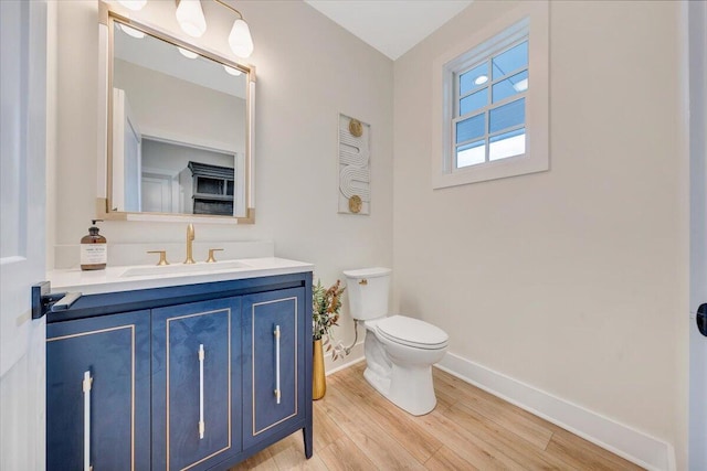 bathroom with baseboards, toilet, wood finished floors, and vanity