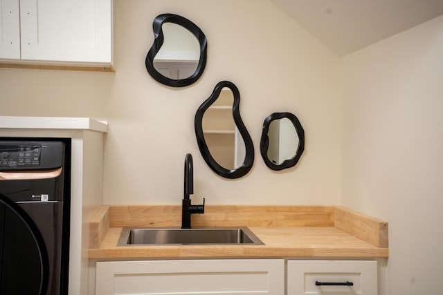 clothes washing area featuring cabinet space, washer / dryer, and a sink