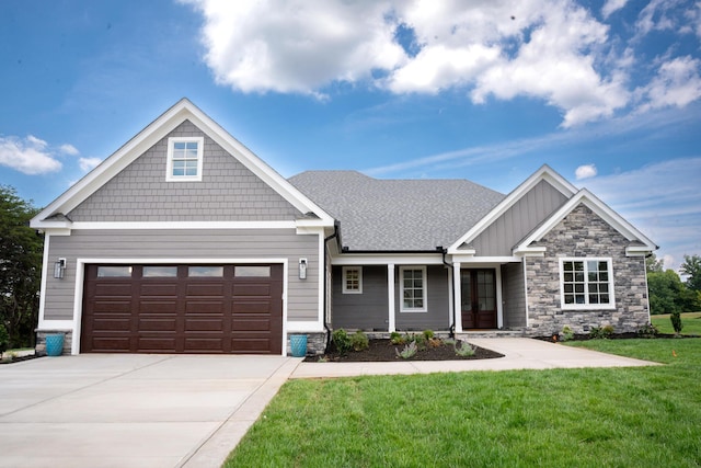 craftsman-style home featuring a front yard, an attached garage, a shingled roof, concrete driveway, and board and batten siding