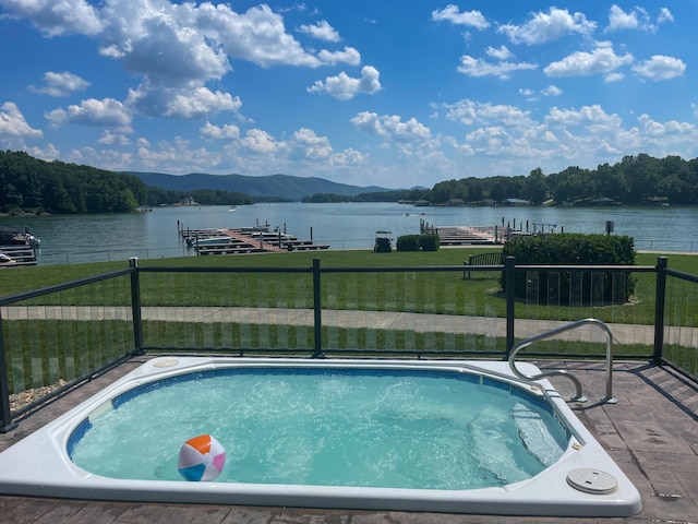 pool with a yard, a water view, and fence