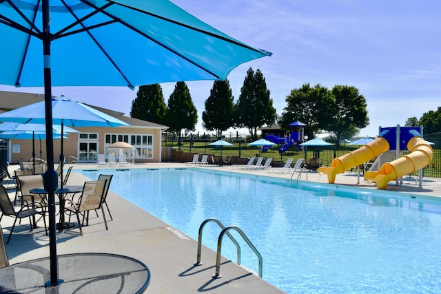 pool with fence, a water slide, and a patio area