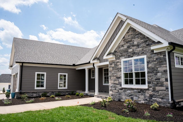 craftsman-style house with stone siding and a shingled roof