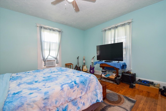 bedroom with hardwood / wood-style flooring, a textured ceiling, cooling unit, and ceiling fan