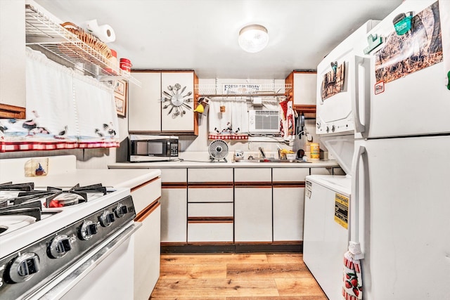 kitchen featuring white cabinetry, sink, cooling unit, light wood-type flooring, and white appliances