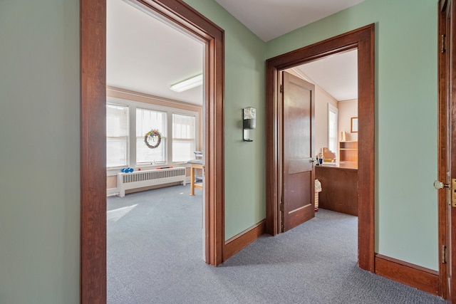 corridor featuring light carpet and radiator