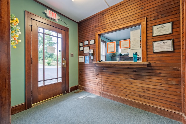 doorway to outside featuring wood walls and carpet floors