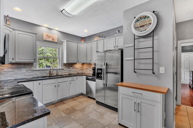 kitchen with sink, stainless steel appliances, tasteful backsplash, white cabinets, and wood counters