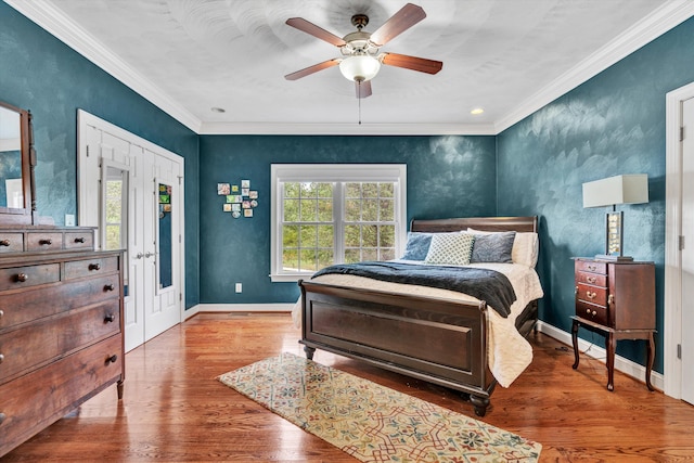 bedroom featuring hardwood / wood-style floors, ornamental molding, and ceiling fan