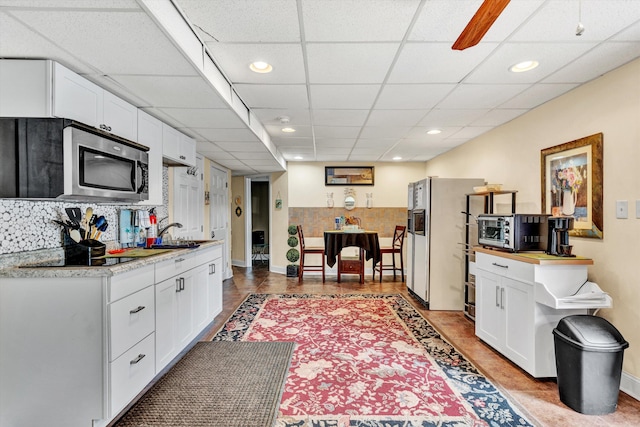 kitchen with light stone counters, black electric stovetop, white refrigerator with ice dispenser, and white cabinets