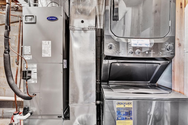 laundry room featuring stacked washer and clothes dryer and heating unit