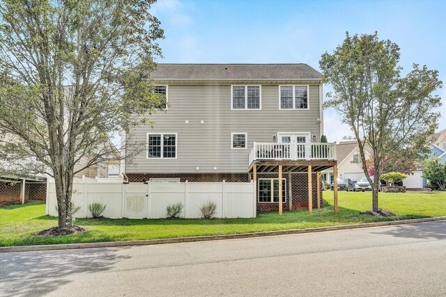 back of property with a wooden deck and a lawn