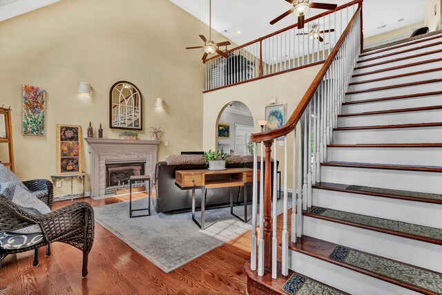 interior space with hardwood / wood-style flooring, a towering ceiling, and ceiling fan