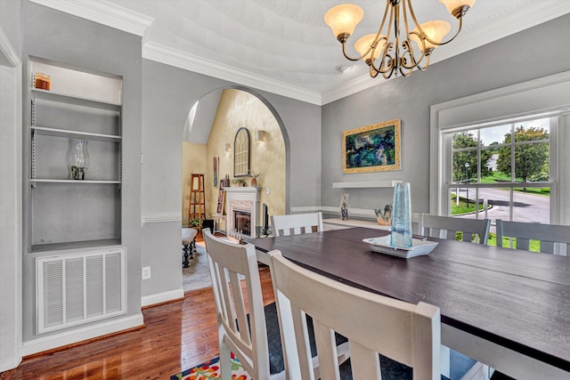 dining area featuring an inviting chandelier, hardwood / wood-style floors, and ornamental molding