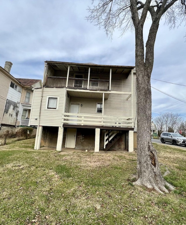 back of property featuring a balcony and a lawn