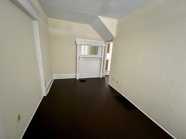 hallway with wood-type flooring and vaulted ceiling